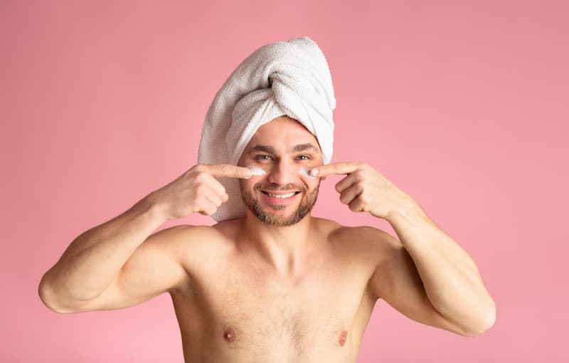 Ein Mann cremt sich bei seiner CBD-Körperpflege mit CBD-Creme im Gesicht ein.